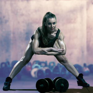 Unlock Your Full Physical Potential A fit, athletic woman stretching in a gym, demonstrating the flexibility and strength needed for peak performance and recovery.