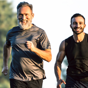 Generations of Strength and Vitality An older and a younger man smiling while jogging together, representing lifelong vitality and the importance of joint support for men's health.