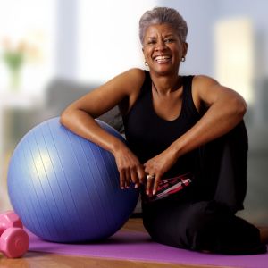 Embrace an Active and Joyful Future A smiling senior woman sitting with her exercise ball and weights, embodying a joyful and proactive approach to healthy aging and mobility.
